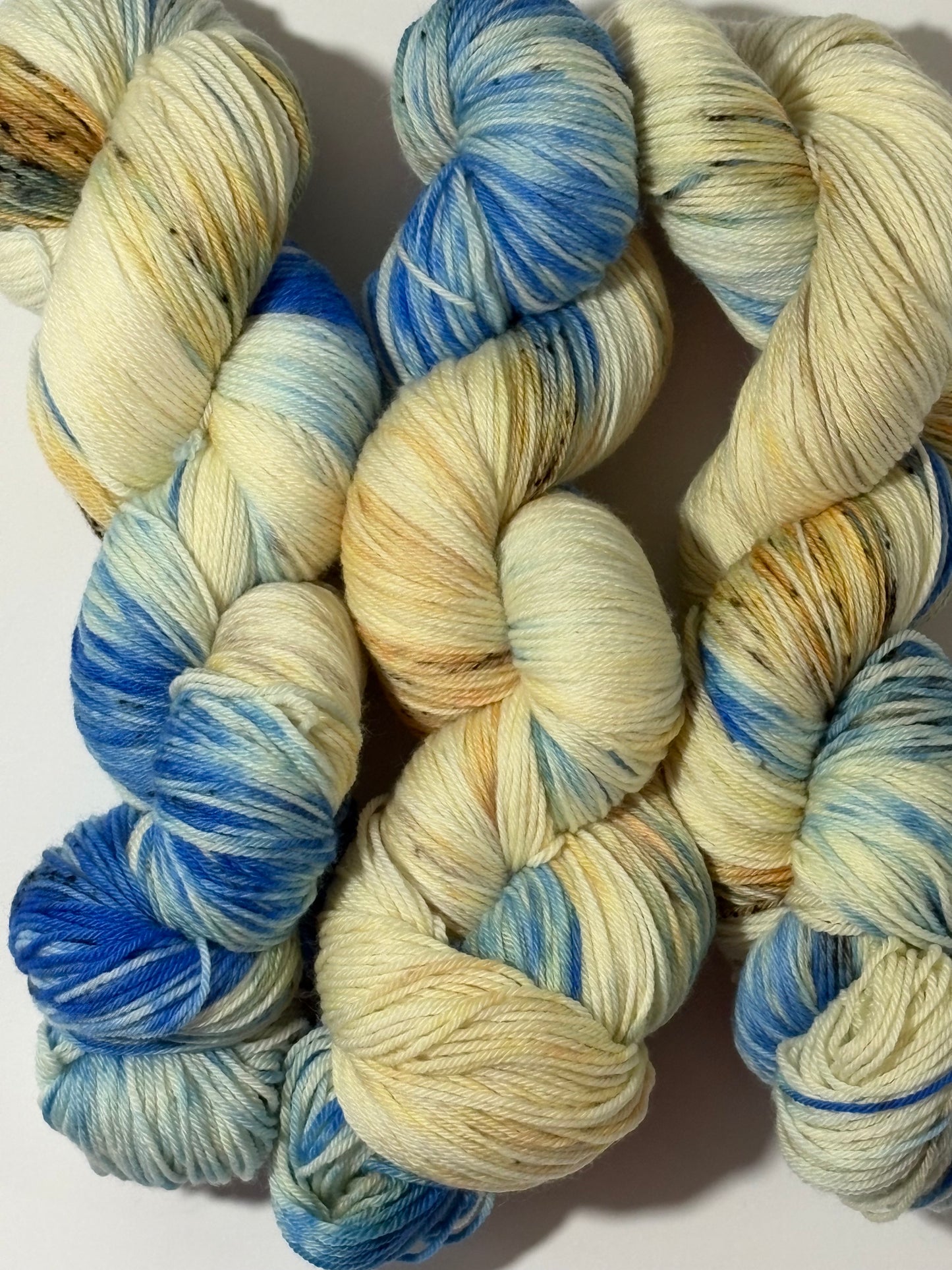 A hand-dyed yarn in a wintery blend of pale blue, soft cream, and earthy speckles inspired by frost-covered branches. Frosted Branches is gentle, natural, and full of quiet detail.