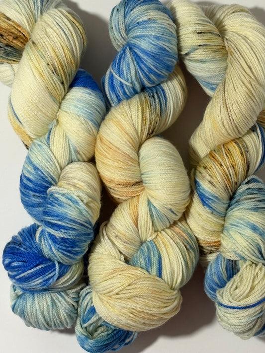 A hand-dyed yarn in a wintery blend of pale blue, soft cream, and earthy speckles inspired by frost-covered branches. Frosted Branches is gentle, natural, and full of quiet detail.