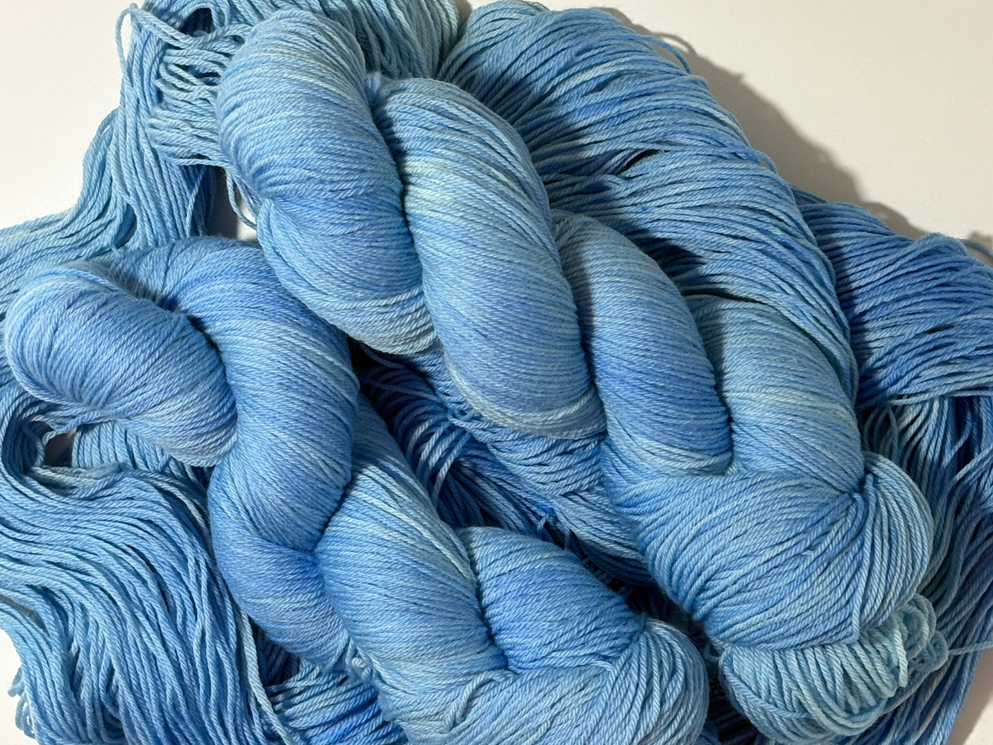 A soft icy blue hand-dyed tonal yarn inspired by frost-covered winter paths and quiet cold mornings.