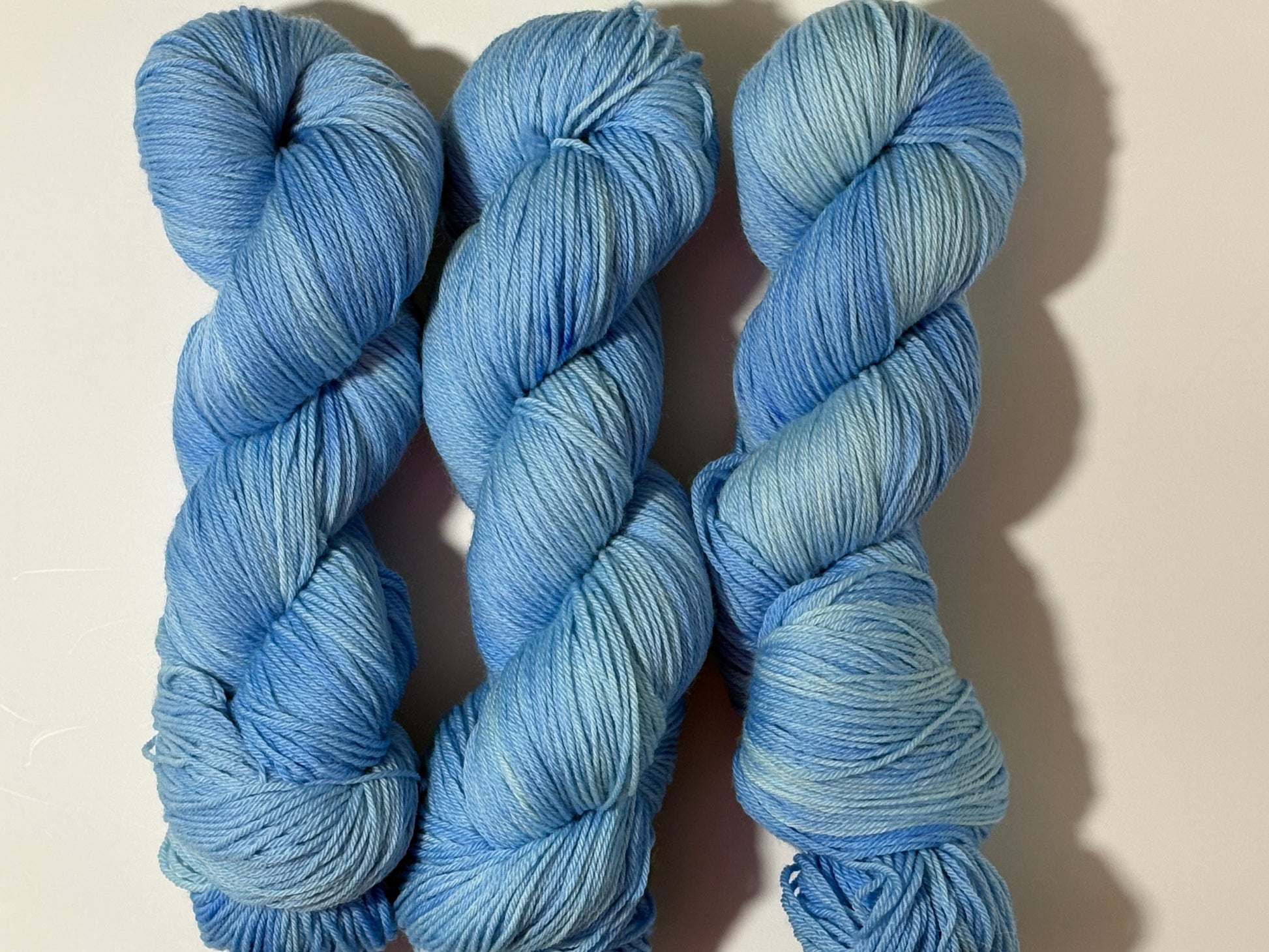 A soft icy blue hand-dyed tonal yarn inspired by frost-covered winter paths and quiet cold mornings.