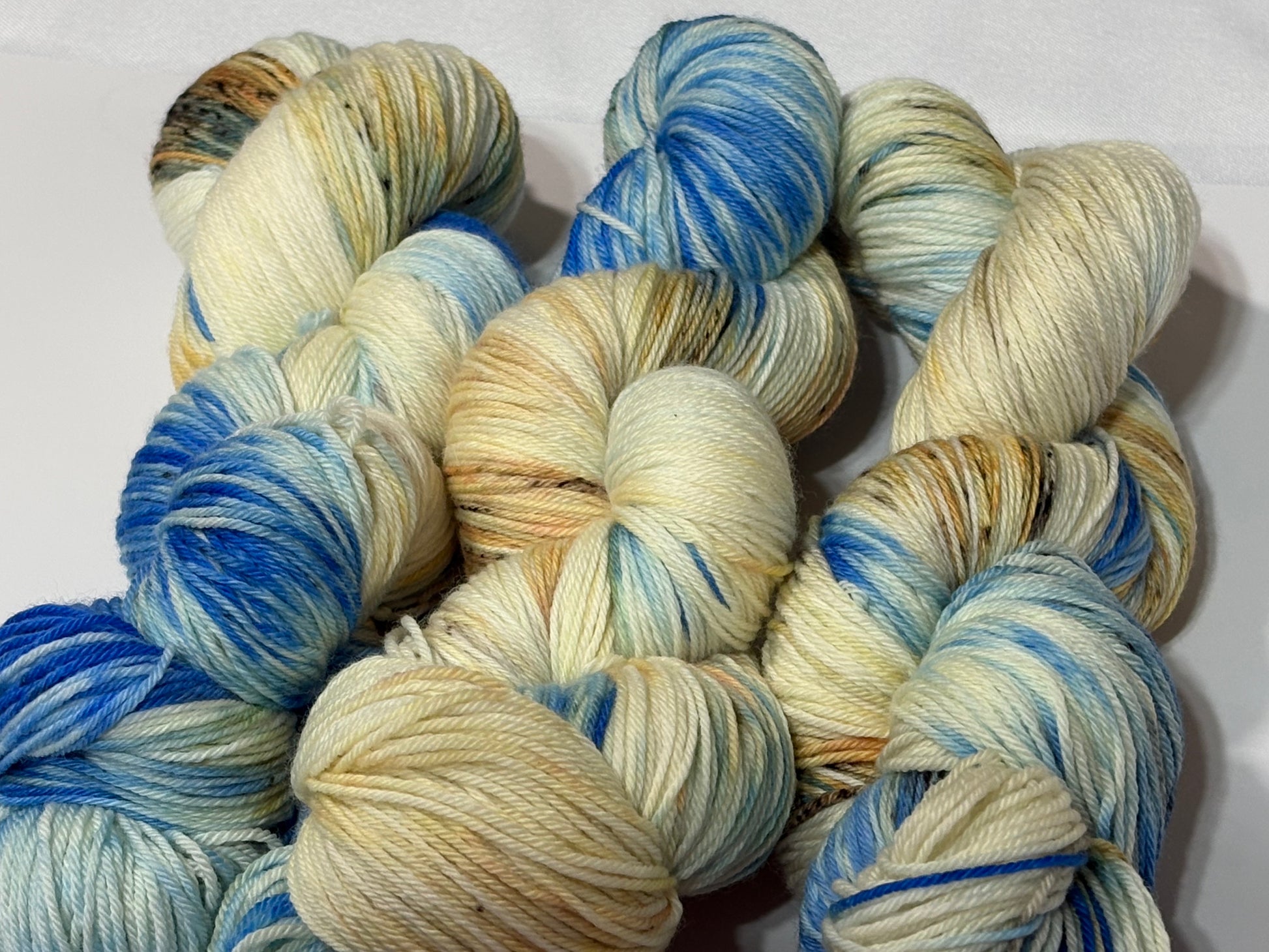 A hand-dyed yarn in a wintery blend of pale blue, soft cream, and earthy speckles inspired by frost-covered branches. Frosted Branches is gentle, natural, and full of quiet detail.