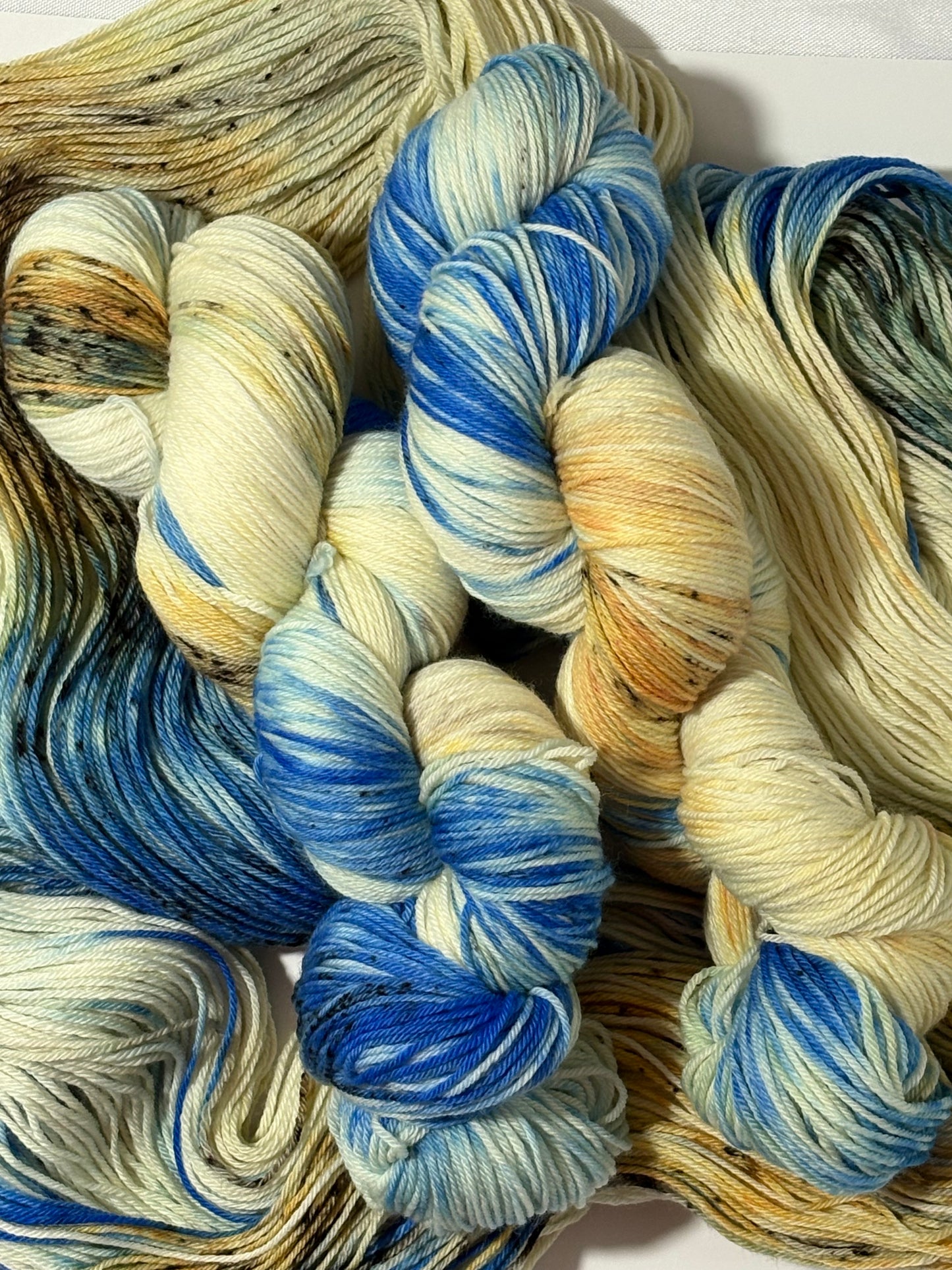A hand-dyed yarn in a wintery blend of pale blue, soft cream, and earthy speckles inspired by frost-covered branches. Frosted Branches is gentle, natural, and full of quiet detail.