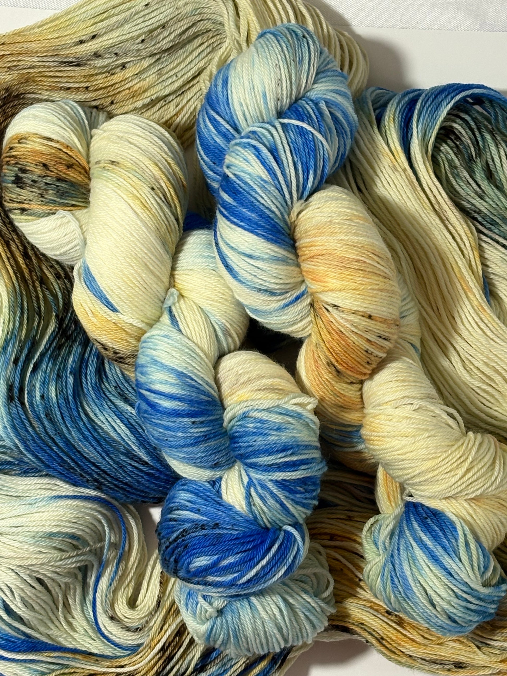 A hand-dyed yarn in a wintery blend of pale blue, soft cream, and earthy speckles inspired by frost-covered branches. Frosted Branches is gentle, natural, and full of quiet detail.