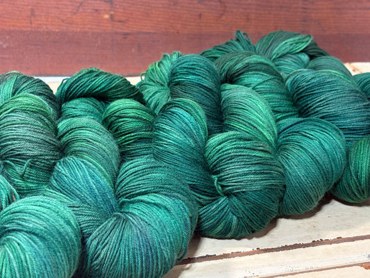 Discover Evergreen Glow — a hand-dyed tonal yarn by The Curious Skein. Small batch, luxury merino wool fingering weight yarn for knitting and crochet.