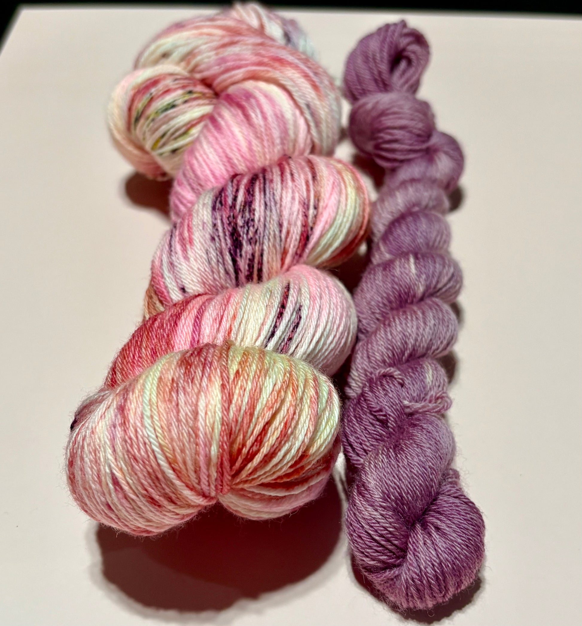 Soft floral sock set with blush pink multicolored skein and coordinating dusty mauve mini skein photographed on a white background.
