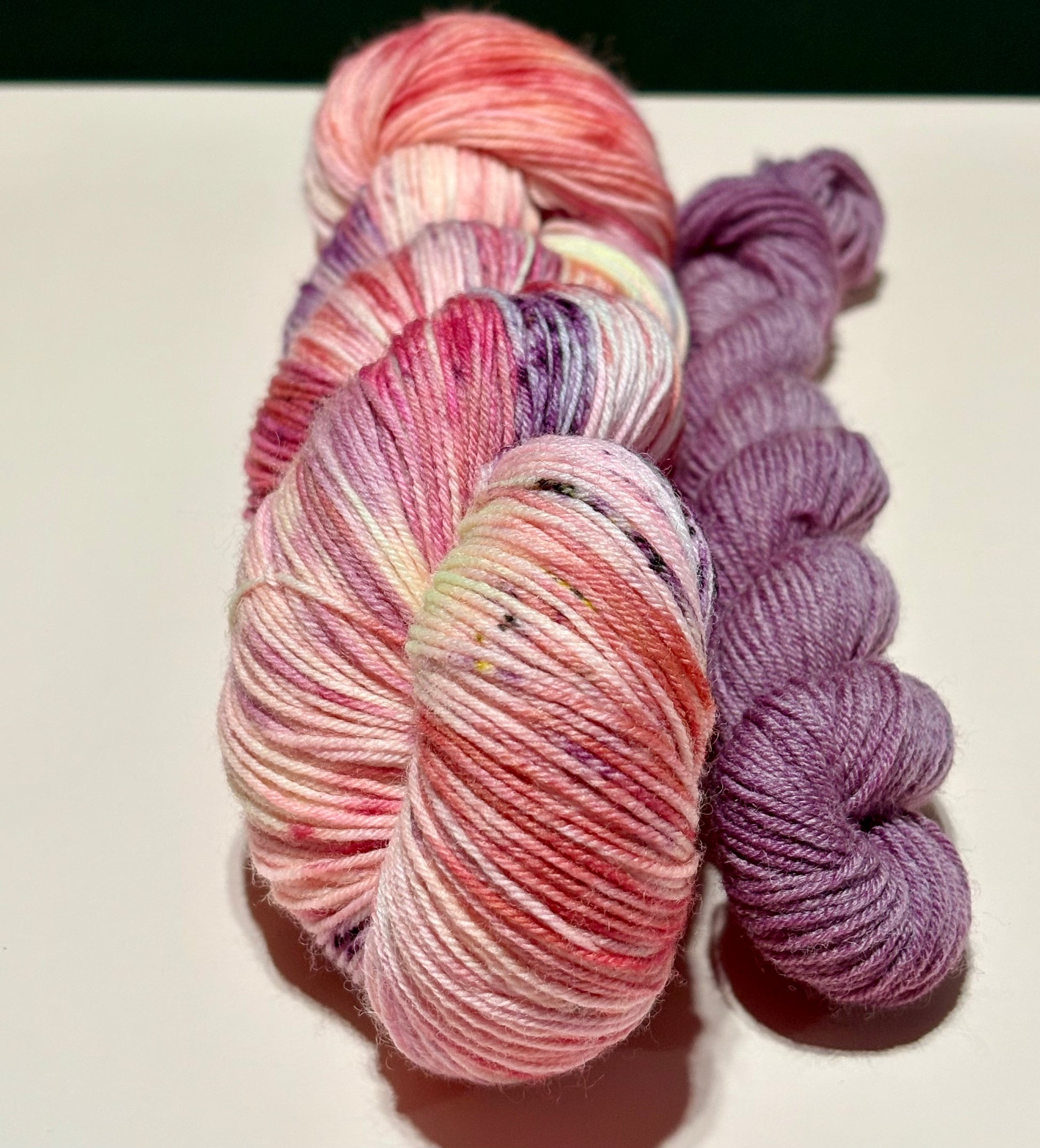 Soft floral sock set with blush pink multicolored skein and coordinating dusty mauve mini skein photographed on a white background.