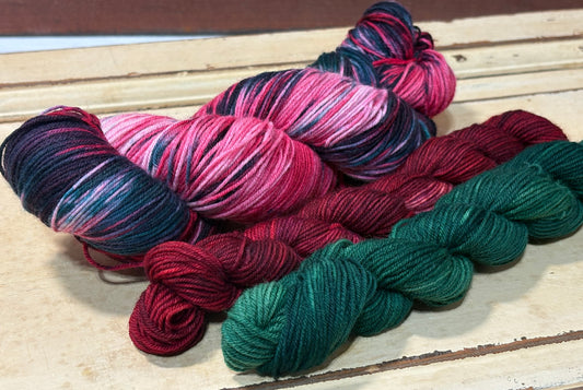 Discover Winterberry Garland Sock Set — a hand-dyed multicolored red and green yarn paired with one red and one green tonal mini skein by The Curious Skein. Small batch, luxury merino nylon blend in fingering weight yarn for socks, shawls and other projects.